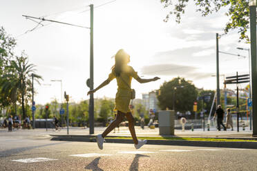 Junge Frau läuft an einem sonnigen Tag auf einer Straße in der Stadt - AFVF06768