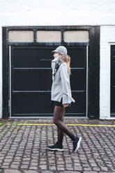 Mid erwachsene Frau in warmer Kleidung zu Fuß auf gepflasterten Straße in der Stadt - JMPF00155