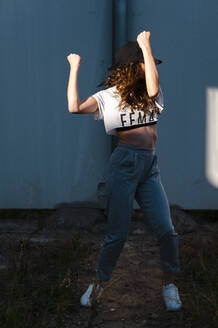 Weibliche Hip-Hop-Tänzerin tanzt gegen die Wand an einem sonnigen Tag - JMPF00175