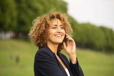 Close-up of smiling businesswoman talking over smart pone while standing outdoors - MJFKF00507