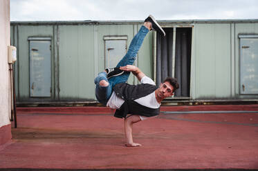Junger Mann beim Breakdance auf der Terrasse eines verlassenen Gebäudes - JMPF00185