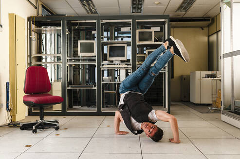 Young man performing stunt on floor in abandoned room - JMPF00190