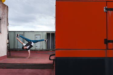 Männlicher Tänzer Breakdance auf verlassenen Gebäude Terrasse gegen bewölkten Himmel - JMPF00194