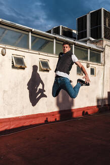 Young man jumping on abandoned building terrace - JMPF00197