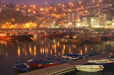 Long exposure of city harbor with moored boats and glowing lights of city in dusk time - ADSF01196