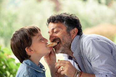 Junge und Vater essen dieselbe Scheibe Brot - CUF55776