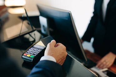 Businessman making contactless payment at hotel reception - CUF55813