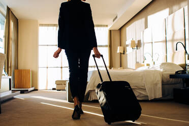Geschäftsfrau mit Gepäck auf Rädern im Hotelzimmer - CUF55820
