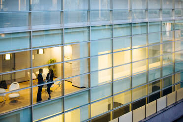 Businessman and businesswoman having discussion by window - CUF55851