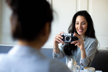 Junge Frau fotografiert Freundin beim Frühstück in einem Boutique-Hotel in Italien - CUF55855