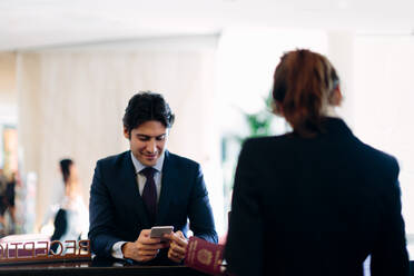 Geschäftsmann beim Einchecken an der Hotelrezeption - CUF55865