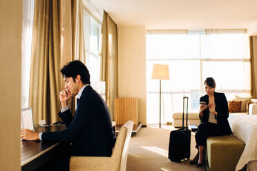 Geschäftsmann und Geschäftsfrau arbeiten im Hotelzimmer - CUF55866