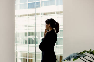 Geschäftsfrau benutzt Mobiltelefon am Fenster - CUF55876
