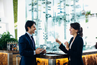 Businessman and businesswoman having drink at bar - CUF55893