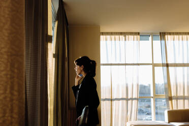 Geschäftsfrau benutzt Mobiltelefon am Fenster - CUF55897