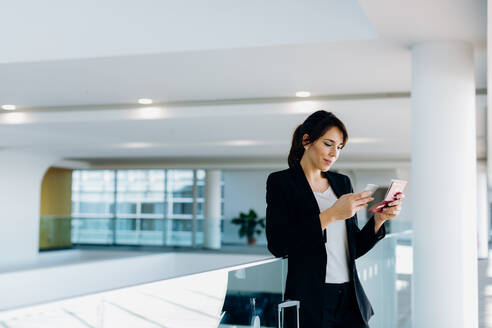 Businesswoman using mobile phone for electronic check-in - CUF55906