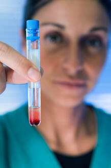 Close up of female doctor holding test tube with red liquid. - CUF55926