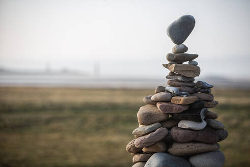 A tower of stones of various sizes stacked in a cairn, the top stone balancing on a point. - CUF55957