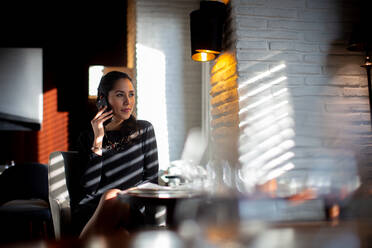 Geschäftsfrau, die an einem Tisch sitzt und ein Mobiltelefon benutzt. - CUF55966