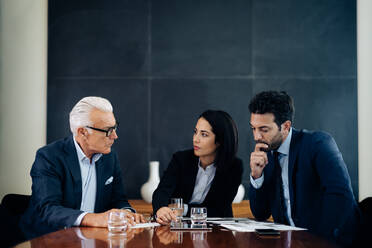 Businessmen and woman having discussion at boardroom table - CUF55972