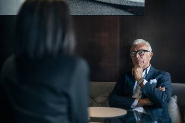 Älterer Geschäftsmann sitzt in Hotel Tisch Sitzung mit Geschäftsfrau, über die Schulter Blick - CUF55984