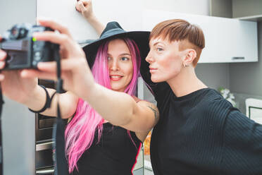 Young woman with long pink hair and woman with short red hair taking selfie. - CUF56106