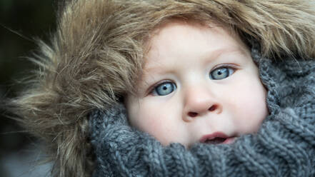 Süßer kleiner Junge in warmer Jacke steht in der Natur und schaut in die Kamera. - ADSF01297