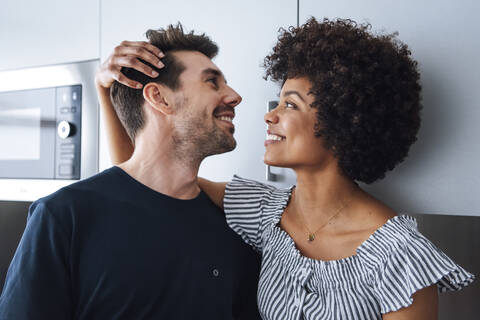 Glückliches multiethnisches Paar in der Küche, lizenzfreies Stockfoto