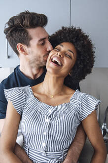 Liebender Mann küsst fröhliche Frau in der Küche - EHF00592