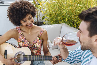 Glückliche Frau spielt Gitarre für Mann trinkt Rotwein auf Penthouse-Terrasse - EHF00604