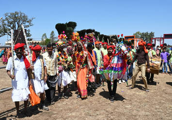 Adivasi-Stammesmänner mit geschmückten Gesichtern und Körpern, die kunstvolle Kopfbedeckungen tragen, tanzen zur Feier des Holi-Festes, Kavant, Gujarat, Indien, Asien - RHPLF16068