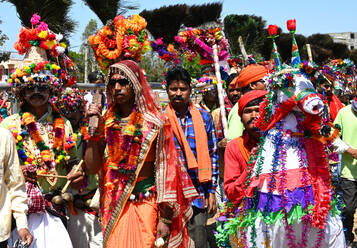 Adivasi-Stammesmänner mit geschmückten Gesichtern und Körpern, die kunstvolle Kopfbedeckungen tragen, tanzen zur Feier des Holi-Festes, Kavant, Gujarat, Indien, Asien - RHPLF16069