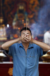 Chinesischer Mann, der Weihrauch verbrennt und für eine glückliche Zukunft betet, Guan Di Chinese Taoist Temple, Kuala Lumpur, Malaysia, Südostasien, Asien - RHPLF16078