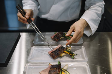 Chefkoch im Restaurant bereitet die Gerichte mit Stäbchen zu - ADSF01401