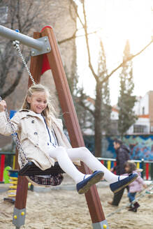 Fröhliches junges Mädchen, das im Park schaukelt und Spaß hat. - ADSF01439