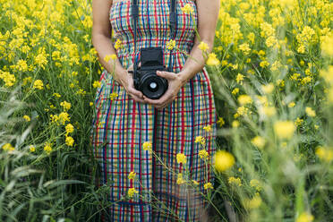 Crop unerkennbar Dame in farbigen Kleid und Jeansjacke hält Foto-Gerät in der Natur - ADSF01446