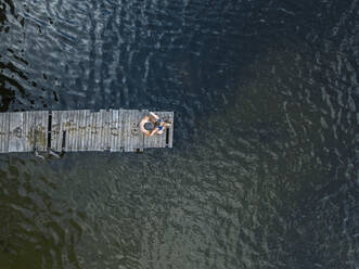 Luftaufnahme eines Mannes und einer Frau, die zusammen am Rande eines Seeuferstegs stehen - KNTF04987
