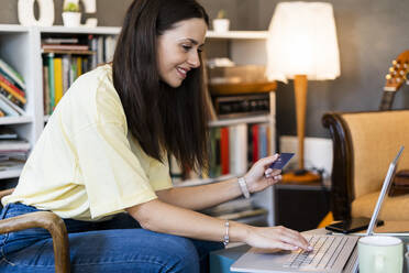 Schöne Frau mit Kreditkarte und Laptop beim Online-Shopping im Café - GIOF08514