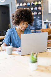 Junge Frau benutzt Laptop in einem Kaffeehaus - GIOF08521