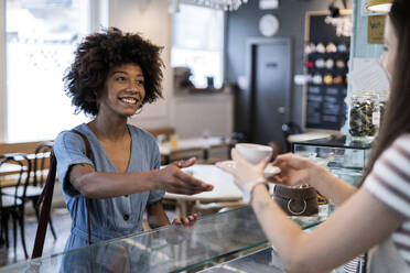 Glückliche Frau nimmt Kaffee vom Besitzer in einem Café - GIOF08555