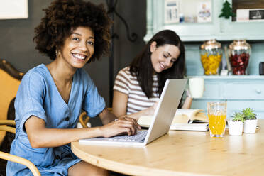 Glückliche Freundinnen studieren mit Laptop in einem Café - GIOF08581