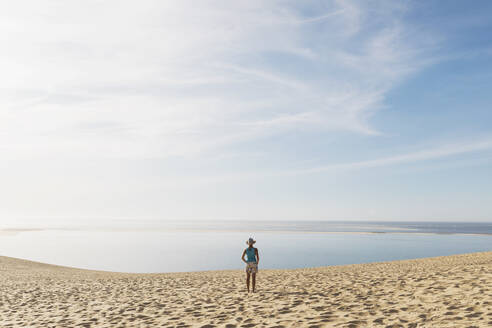 Woman looking at Atlantic ocean while standing on beach during sunny day, Dune of Pilat, Nouvelle-Aquitaine, France - GWF06626