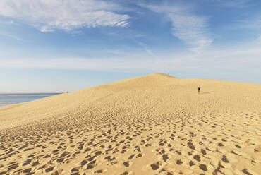 Mid distance view of man walking on sand dune against sky, Dune of Pilat, Nouvelle-Aquitaine, France - GWF06633