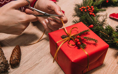 Crop Frau bindet eine Schleife von einem Weihnachtsgeschenk Übergabe der Dekoration - ADSF01601