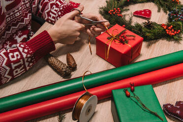 Crop Frau bindet eine Schleife von einem Weihnachtsgeschenk Übergabe der Dekoration - ADSF01602