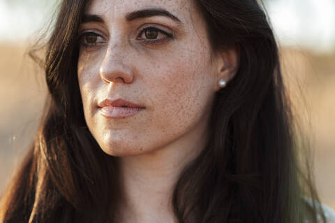 Close-up of thoughtful young woman with long hair during sunset stock photo