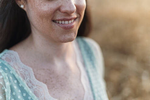 Close-up of smiling woman with freckles on face during sunset - JMPF00214