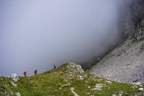 Männliche Wanderer auf einem Berg bei nebligem Wetter in den Bergamasker Alpen, Italien - MCVF00532