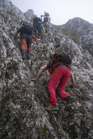 Männliche Wanderer mit Rucksäcken beim Klettern auf einem Berg, Bergamasker Alpen, Italien, lizenzfreies Stockfoto