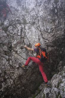 Älterer Mann mit Rucksack beim Klettern auf einem Berg, Bergamasker Alpen, Italien - MCVF00536